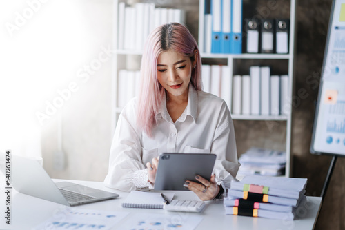 Asian businesswoman working in the office with working notepad, tablet and laptop documents .