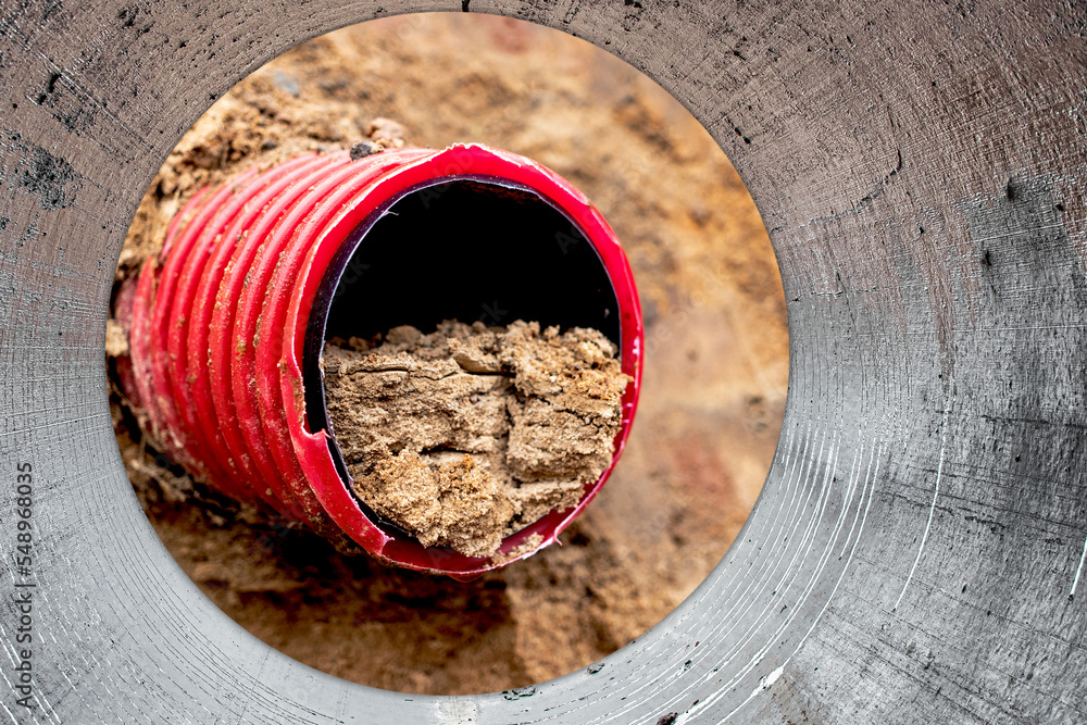 Clogged water or sewer pipes. Pipe cleaning. Underground pipeline works.  Repair work on the pipeline. Underground communications. Water supply at  home. View from the big pipe. Photos | Adobe Stock