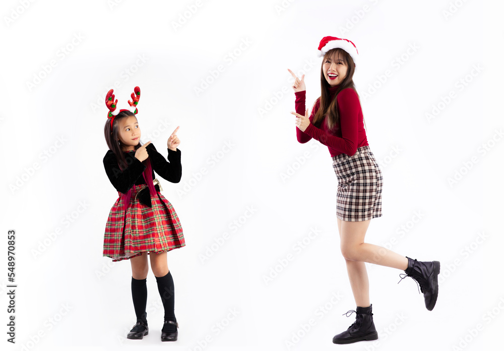 Young asian woman and girl in red christmas theme costume wear santa hat posing finger pointing standing full length white background. Merry Christmas. Young asian woman and girl in red christmas theme costume wear santa hat posing finger pointing standing full length white background. Merry Christmas.