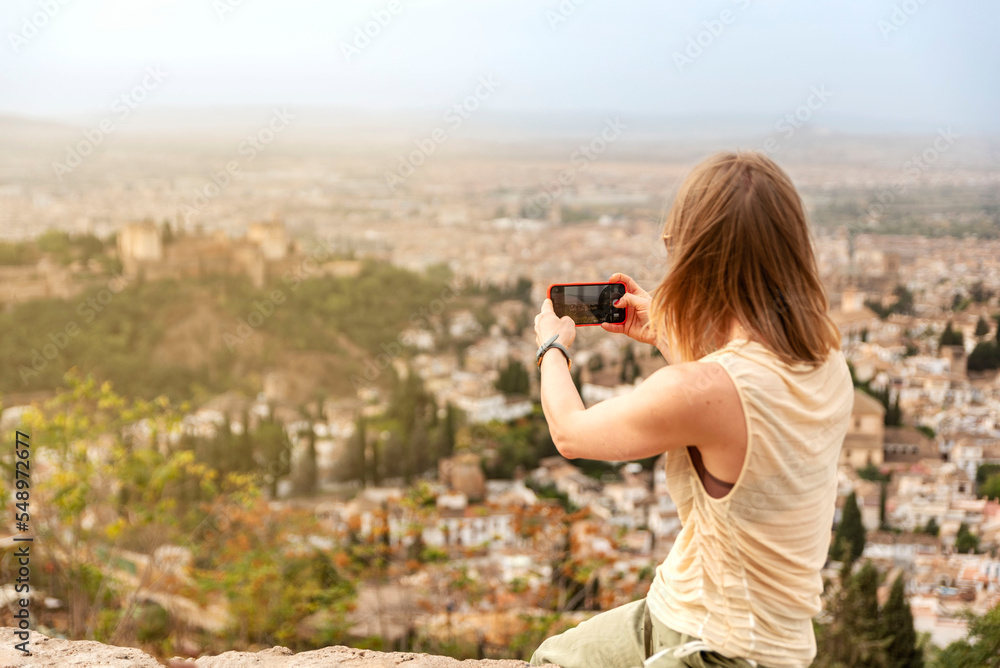 woman in a viewpoint of the city of Granada contemplating views and taking a picture woman in a viewpoint of the city of Granada contemplating views and taking a picture