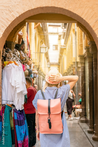 back view of female backpacker visiting Granada, Spain. walking trough local market Alcaiceria, cityscape destination in Andalusia.Holidays in Europe
