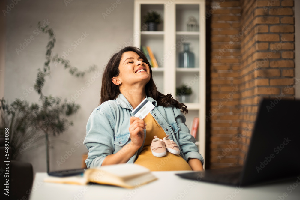 Pregnant woman shopping online at home. Happy woman with laptop and credit card.. Pregnant woman shopping online at home. Happy woman with laptop and credit card..