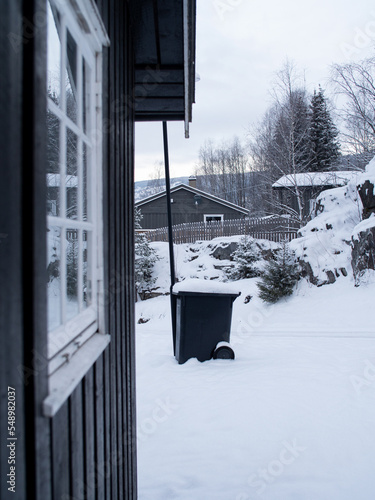 White vintage window in a black wooden house in a snow-covered landscape in Norway