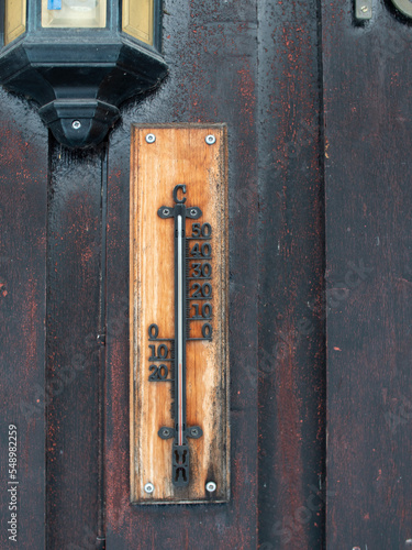 Old worn thermometer placed outside in the cold on old painted wodden facade