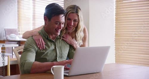 Couple, laptop and browsing online to book a vacation for a travel getaway in the family home. Pc, internet and man and woman searching holiday destinations while sitting at the dining table photo