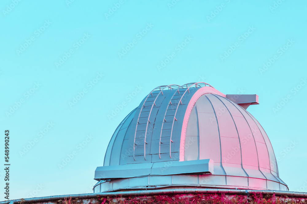 White coral pink dome of a large telescope in the Observatory at sunset on blue pastel sky