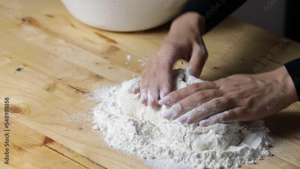 women's hands knead dough, cooking pizza in kitchen, close-up, flour on wooden table women's hands knead dough, cooking pizza in kitchen, close-up, flour on wooden table
