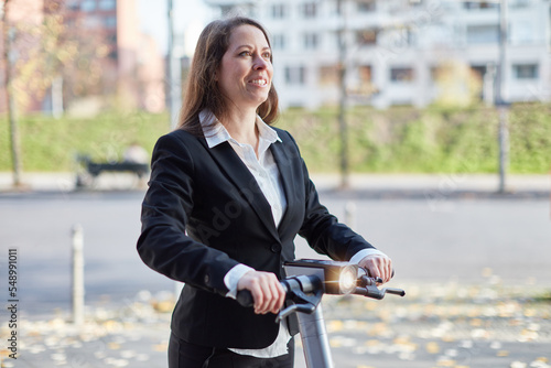 Businesswoman using e-scooter to commute to work in city photo