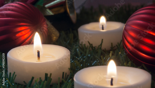 image with three lighted candles and christmas ornaments