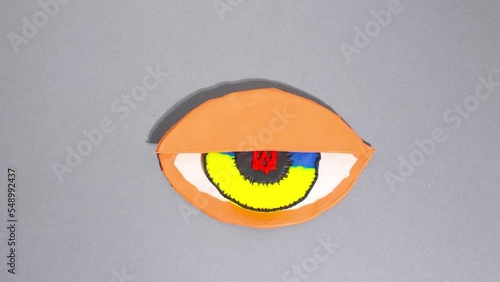 Plasticine claymotion stop motion animation, a large plasticine eye with a Ukrainian patriotic pupil of blue-yellow color, with a red coat of arms of Ukraine. The eyelid rises and falls photo