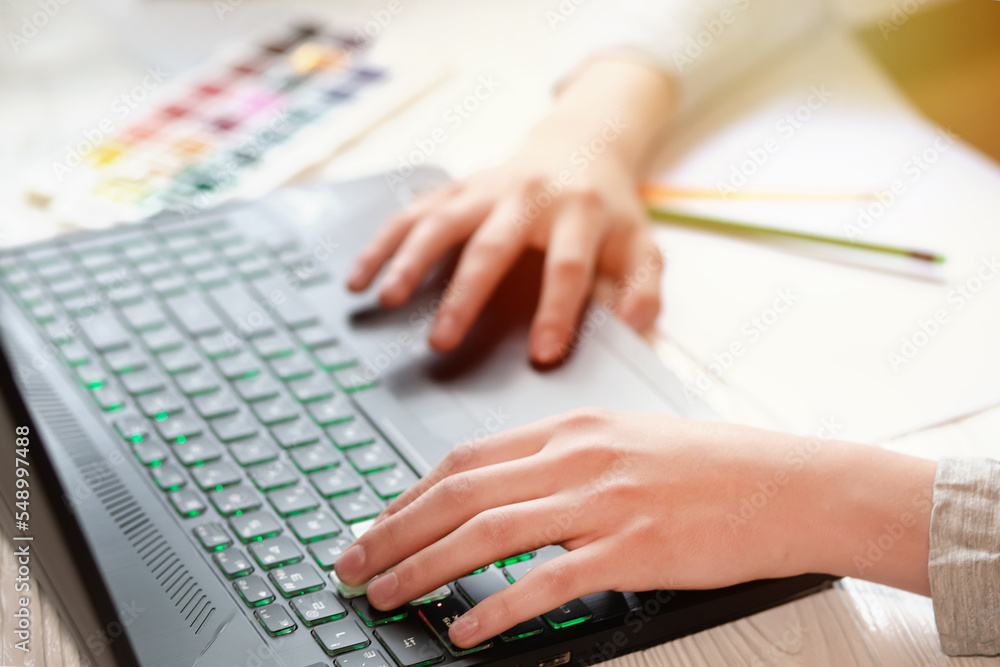 The laptop keyboard is black. Beautiful hands on laptop keys near paints and pencils. Online drawing courses The laptop keyboard is black. Beautiful hands on laptop keys near paints and pencils. Online drawing courses