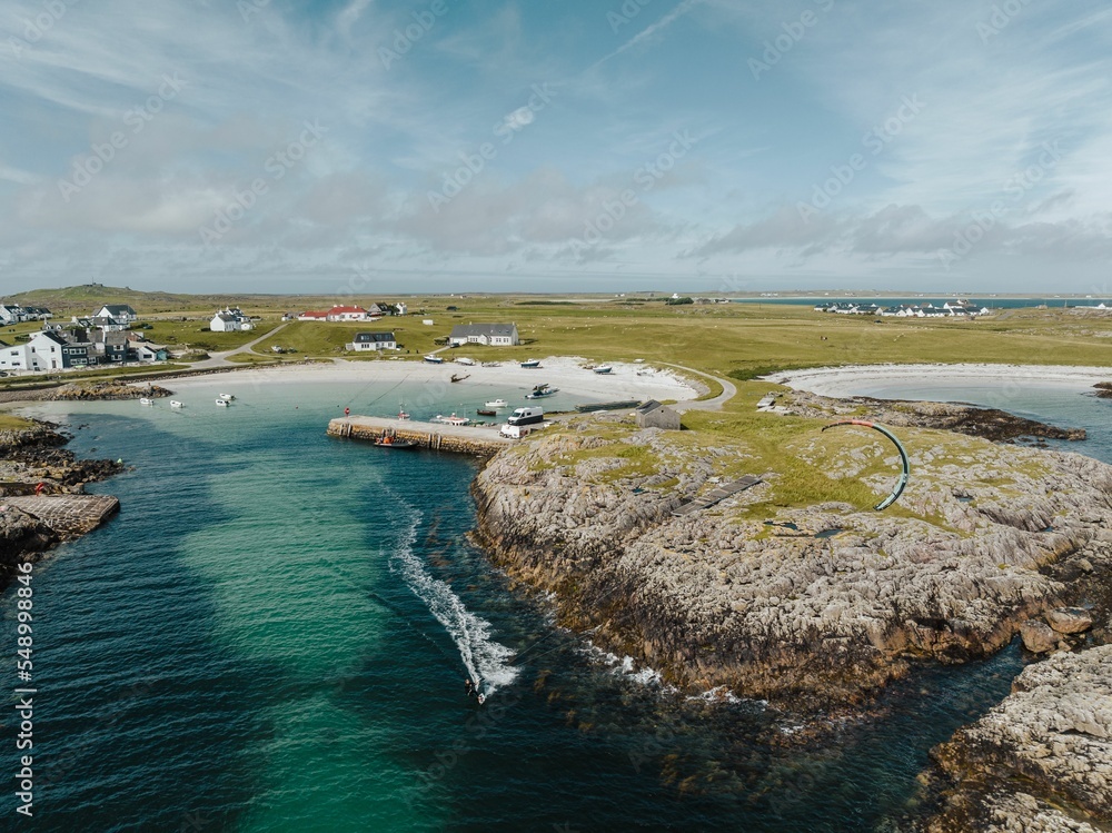 Fototapeta premium Aerial view of a sandy beach along Tiree island in Scotland with houses and a turquoise sea lagoon
