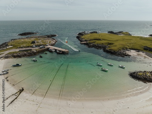 Aerial view of a kite surfer in water along Tiree island in Scotland with a sandy beach and seascape