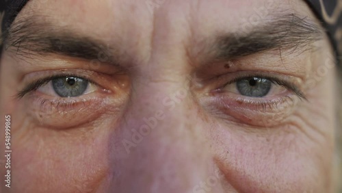 Close-up of happy mature male face with grey eyes and wrinkles.
