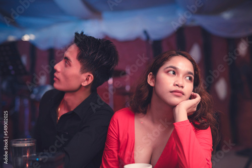 A couple having a date at an elegant restaurant sits back to back and ignores each other as they are having an argument. A lady is upset with her insensitive boyfriend. Waiting for the night to end.