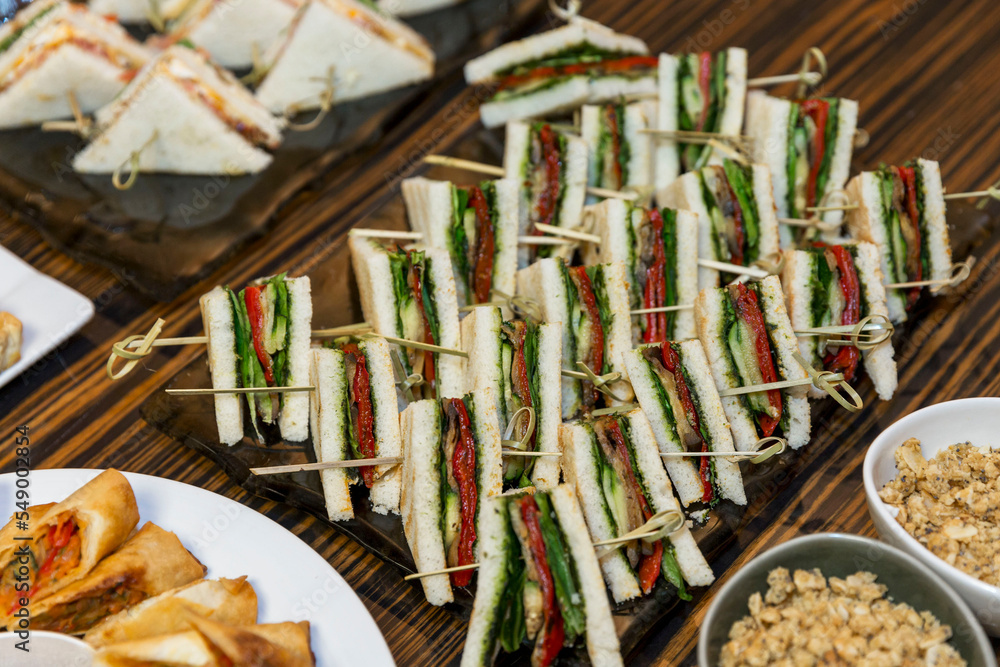 Appetizing triangular club sandwiches on the buffet table. Catering for events and holidays and business meetings. Close-up.