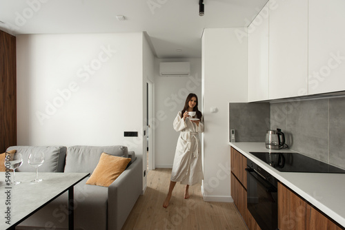 beautiful woman stand with a cup of tea in hands in the kitchen. apartment after renovation