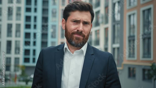 Confused worried caucasian businessman stand in city doubtful man shrug shoulders uncertain position don't know unsure complicated answer negative feedback false attitude disagree difficult questions