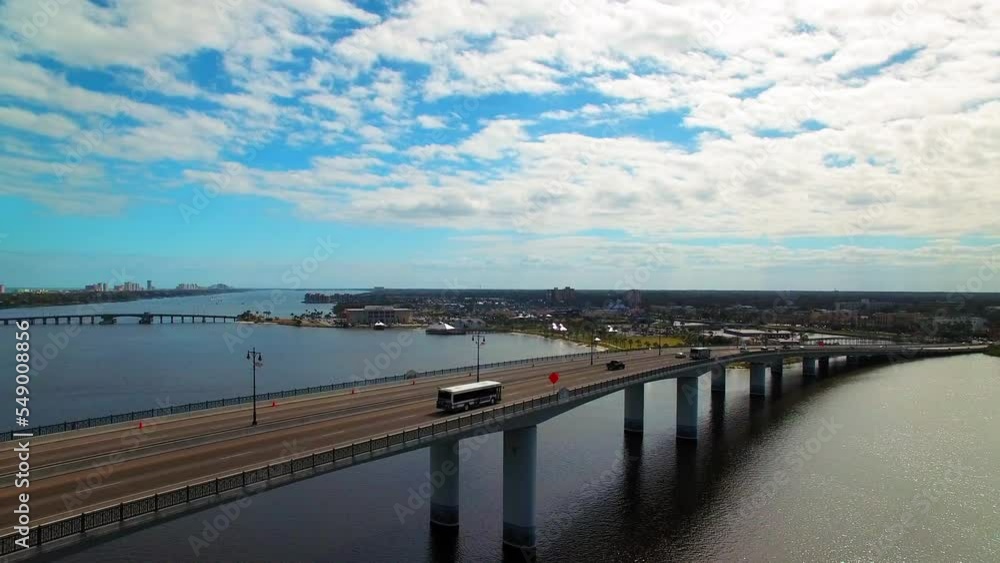Aerial Panning Shot Of Vehicles Moving On Bridge In City Under Clouds, Drone Flying Over Sea - Daytona Beach, Florida Aerial Panning Shot Of Vehicles Moving On Bridge In City Under Clouds, Drone Flying Over Sea - Daytona Beach, Florida