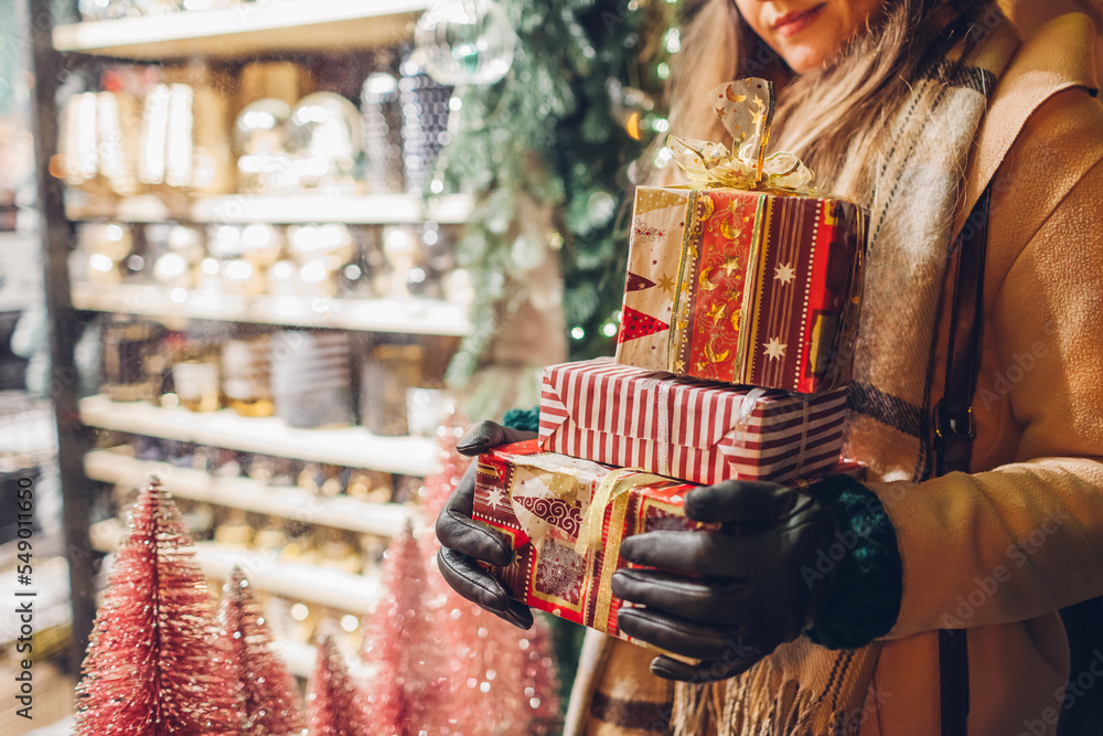 Close up of Christmas gift boxes in female hands. Woman holding presents after New year shopping - obrazy, fototapety, plakaty 
