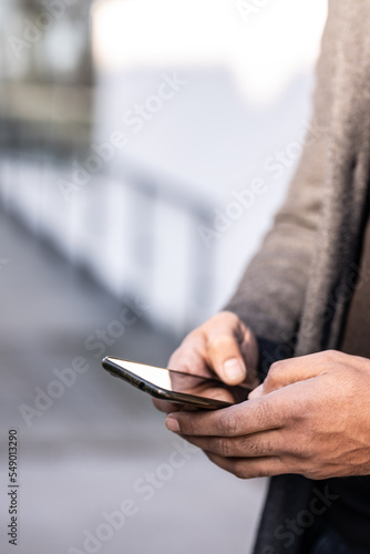 Close up of business man hands using modern technology, mobile phone and laptop outdoors