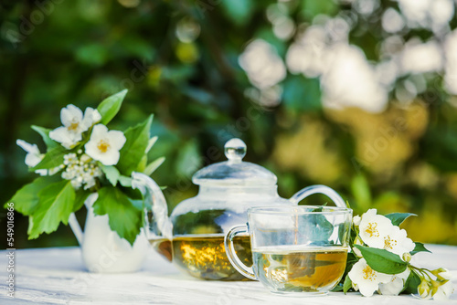 Philadelphus or garden jasmine flowers, healthy herbal tea cup of hot tea. Romantic dinner with therapeutic fragrant tea.