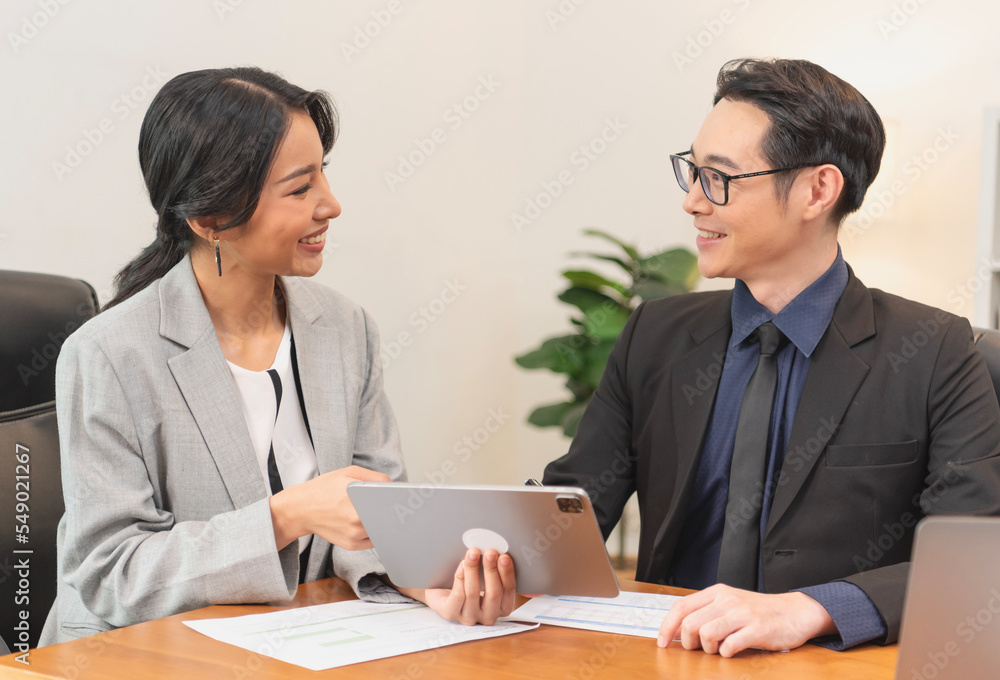Smiling asian businesswoman showing tablet to her manager during a meeting in the office. secretary and boss in the office discuss new strategies and business development plans. Smiling asian businesswoman showing tablet to her manager during a meeting in the office. secretary and boss in the office discuss new strategies and business development plans.