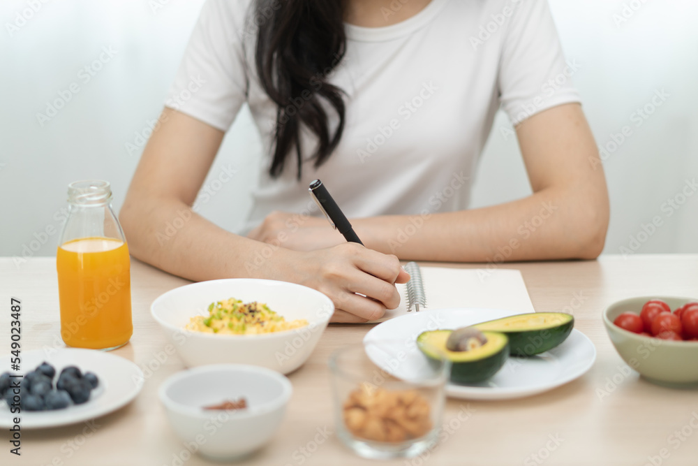 young female planning menu to eat ketogenic diet during weight loss program. young female planning menu to eat ketogenic diet during weight loss program.