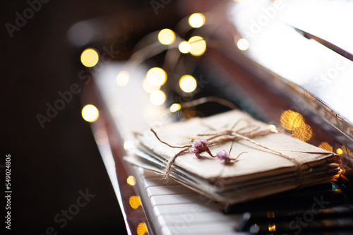 фотографія Paper snail mail letters in envelope on piano keys with dry flowers over glow Christmas lights close up