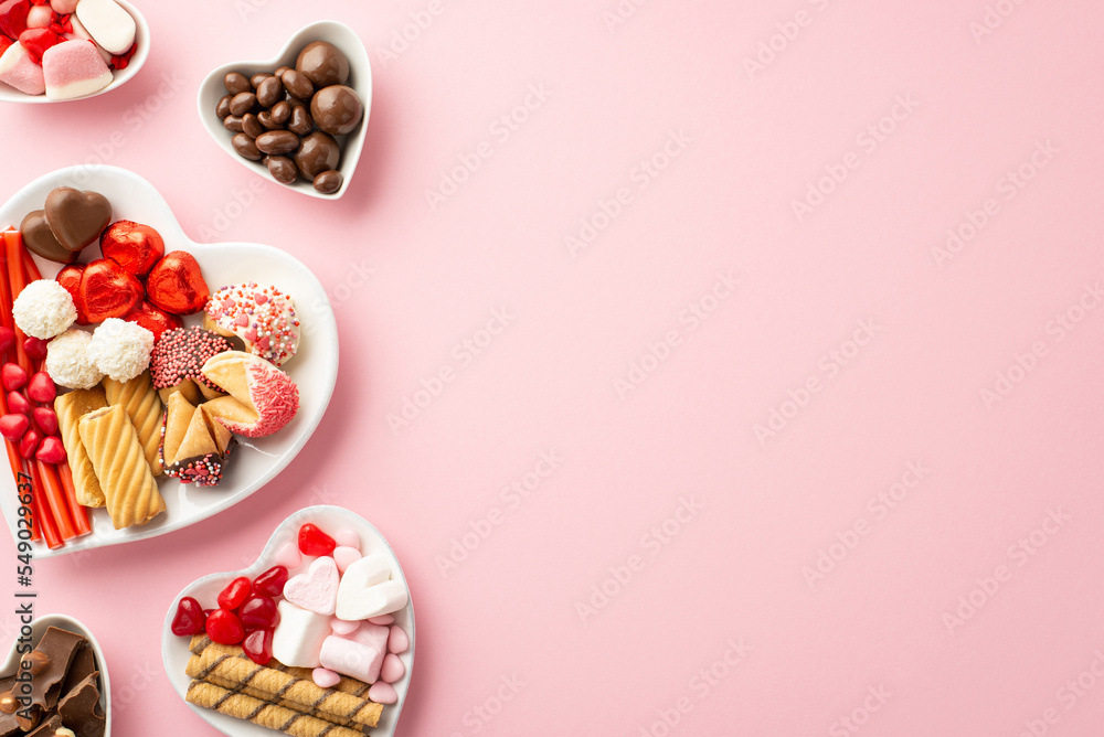 Valentine's Day concept. Top view photo of heart shaped saucers with sweets candies on isolated pastel pink background with copyspace Valentine's Day concept. Top view photo of heart shaped saucers with sweets candies on isolated pastel pink background with copyspace