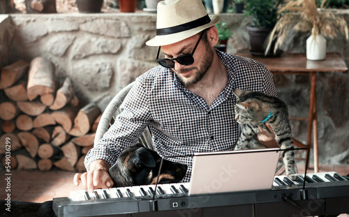 Bearded man musician in straw hat with his cat and dog playing electric piano. photo