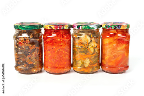 Homemade pickles in glass jars on a white background. Four jars of pickles. Canned vegetable salads.