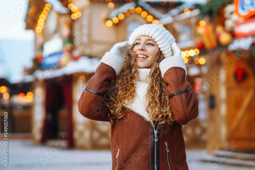 Smiling woman posing at festive street market. Festive Christmas fair, winter holidays concept.