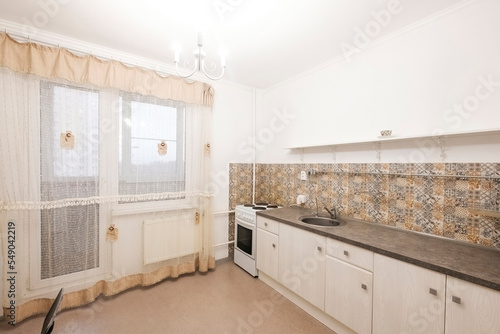 bright large kitchen in the apartment with a kitchen set and access to balcony