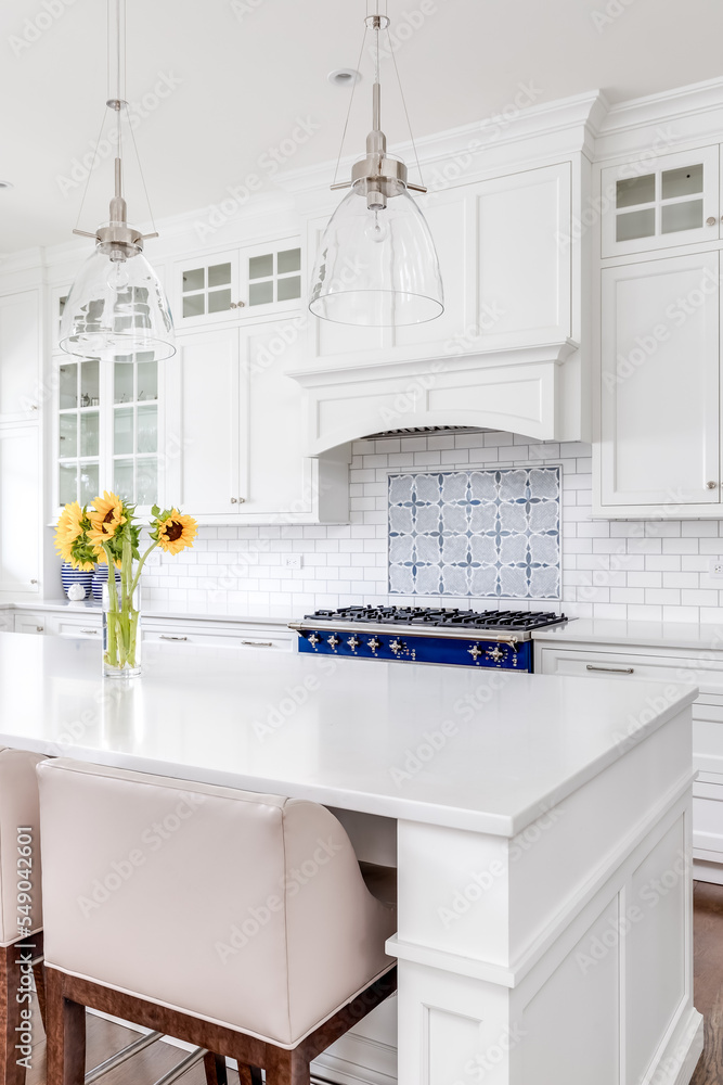 A luxury white kitchen with bar stools sitting at a large island