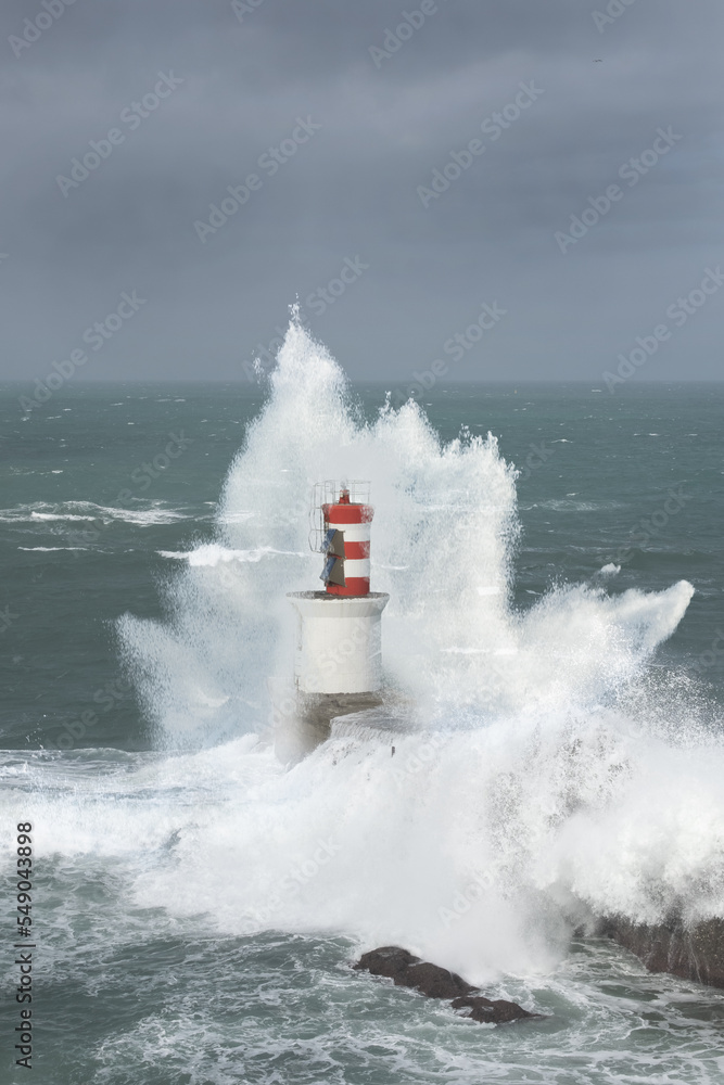 Strong waves crash against the lighthouse.