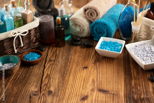 Spa and wellness concept. Bottles with bath and spa cosmetics, rolled up towels, bath salts and care products on wooden rustic paneling.