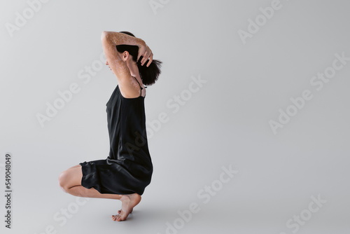 Barefoot woman with vitiligo touching hair on grey background.