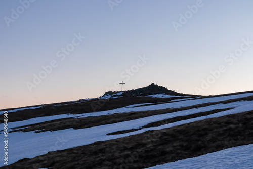 Scenic evening view after sunset on summit cross of mountain peak Zingerle Kreuz, Saualpe, Lavanttal Alps, Carinthia, Austria, Europe. Hiking trail Wolfsberg. Sky in soft colors creating calm vibes photo