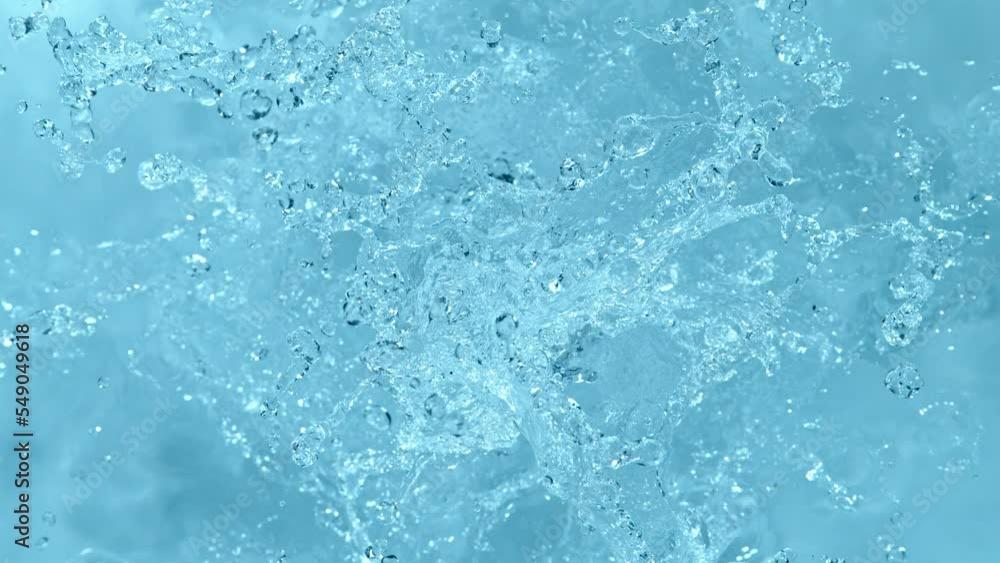 Super slow motion of splashing water on blue background. Filmed on high speed cinema camera, 1000 fps. High angle view, studio shot. Super slow motion of splashing water on blue background. Filmed on high speed cinema camera, 1000 fps. High angle view, studio shot.