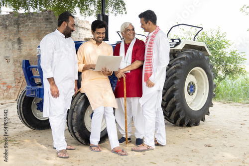Photography Young man guiding farmer about modern farming techniques using laptop on agriculture field