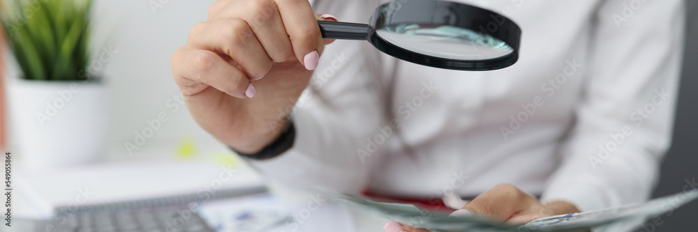 Female hold magnifying glass analyzing business financial data, manager calculates company finances