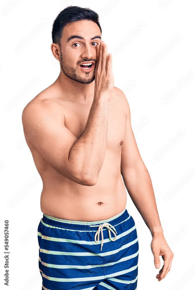 Fototapeta premium Young handsome man wearing swimwear hand on mouth telling secret rumor, whispering malicious talk conversation