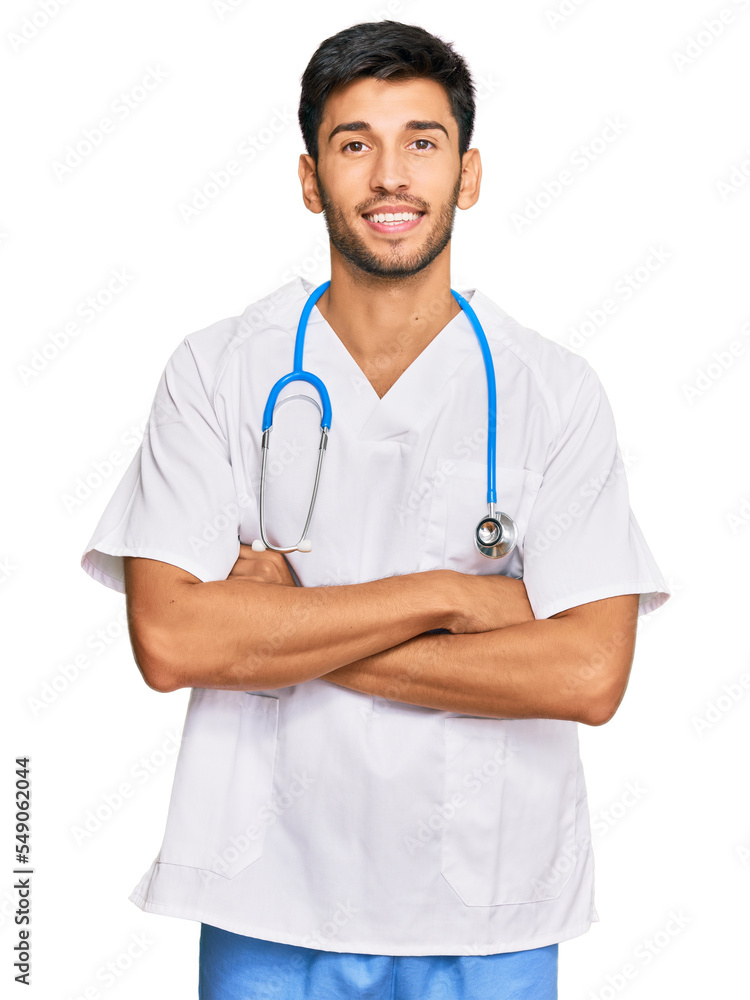 Young handsome man wearing doctor uniform and stethoscope happy face smiling with crossed arms looking at the camera. positive person. Young handsome man wearing doctor uniform and stethoscope happy face smiling with crossed arms looking at the camera. positive person.