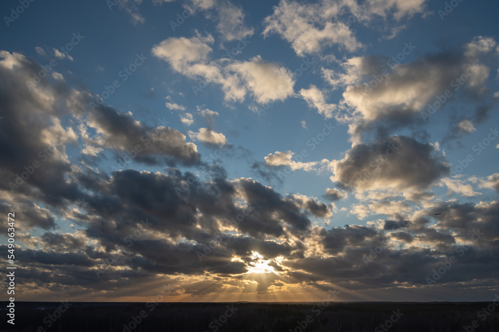 Scenic sunset over the forest with sun rays breaking through clouds