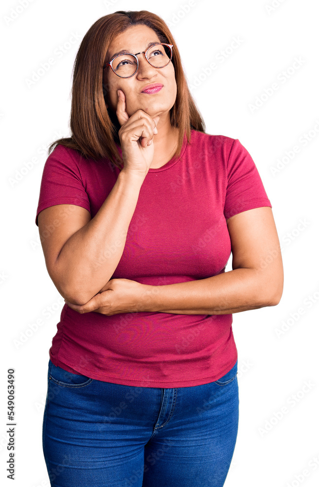 Middle age latin woman wearing casual clothes and glasses serious face thinking about question with hand on chin, thoughtful about confusing idea Middle age latin woman wearing casual clothes and glasses serious face thinking about question with hand on chin, thoughtful about confusing idea
