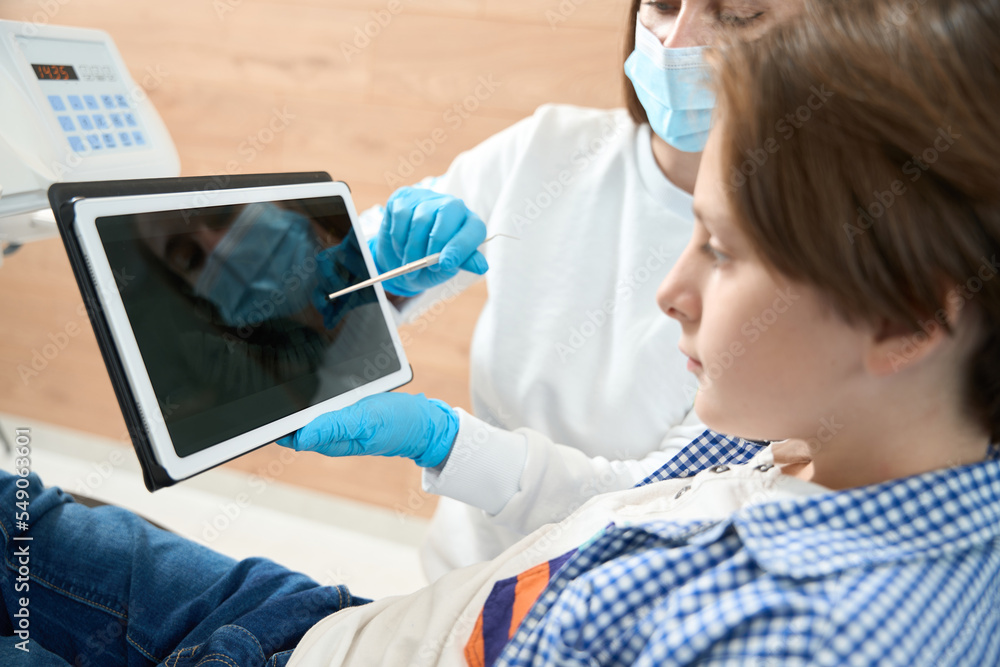 Fototapeta premium Woman dentist consults a young patient in a dental office