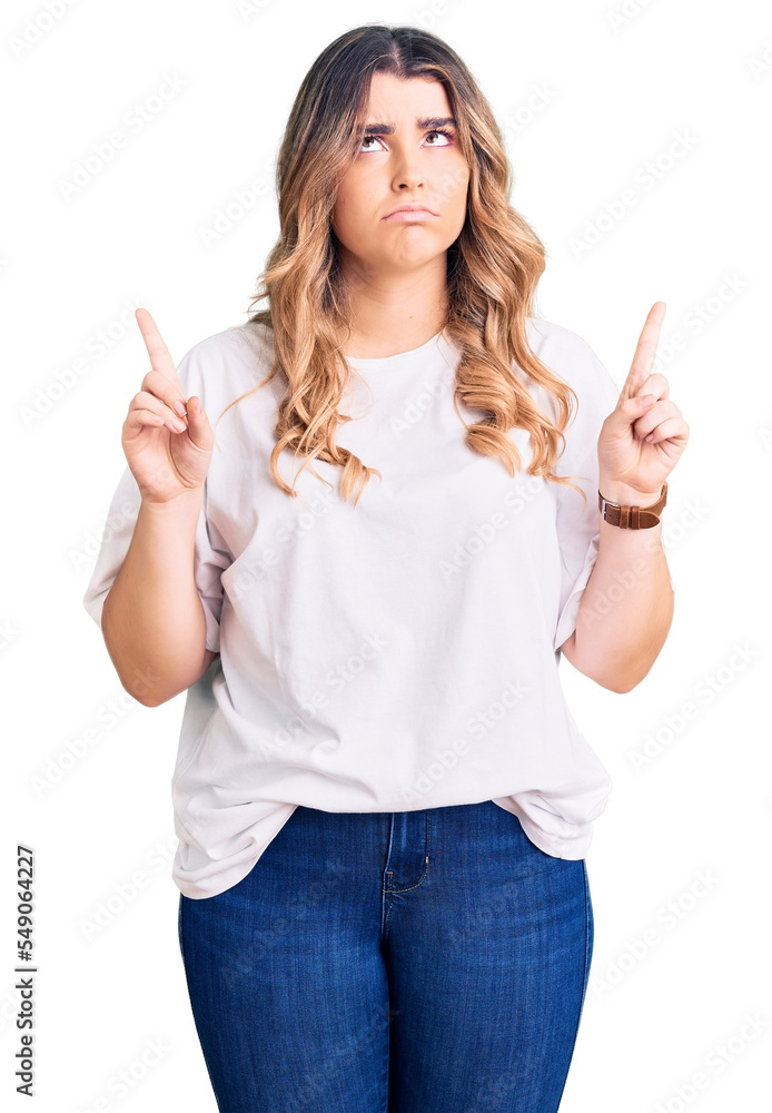 Young caucasian woman wearing casual clothes pointing up looking sad and upset, indicating direction with fingers, unhappy and depressed. Young caucasian woman wearing casual clothes pointing up looking sad and upset, indicating direction with fingers, unhappy and depressed.
