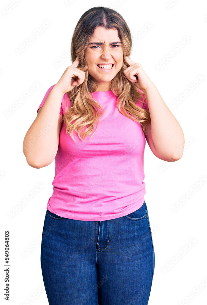 Young caucasian woman wearing sportswear covering ears with fingers with annoyed expression for the noise of loud music. deaf concept. Young caucasian woman wearing sportswear covering ears with fingers with annoyed expression for the noise of loud music. deaf concept.