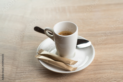 White cup of coffee on a saucer with a spoon, morning coffee on a light background